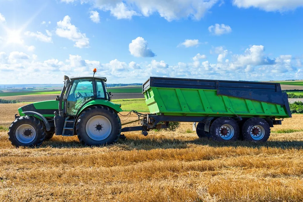 Side view of a Green Tractor in Wheat Field with a Green Trailer with BKT tyres fitted