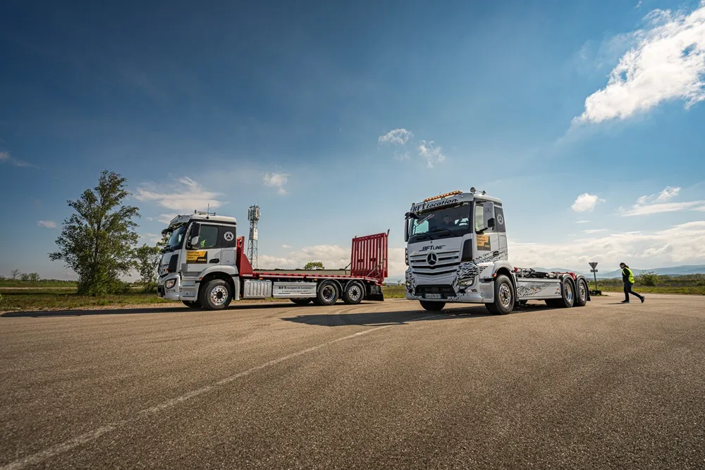 Two white racing trucks parked on tarmac with a blue sky background