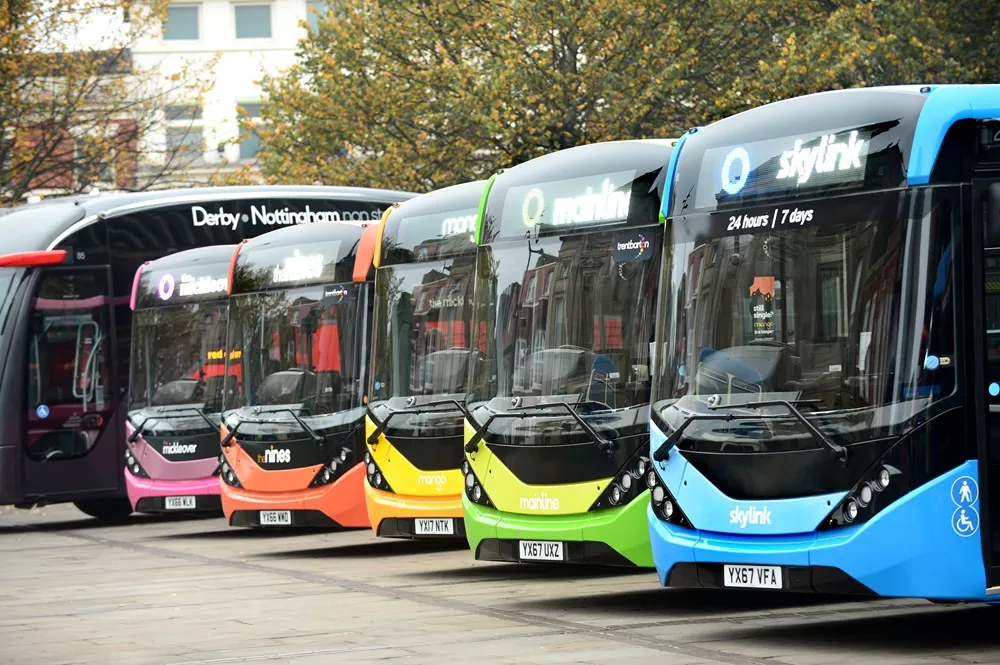 Front side view of parked Trentbarton buses of many colours.