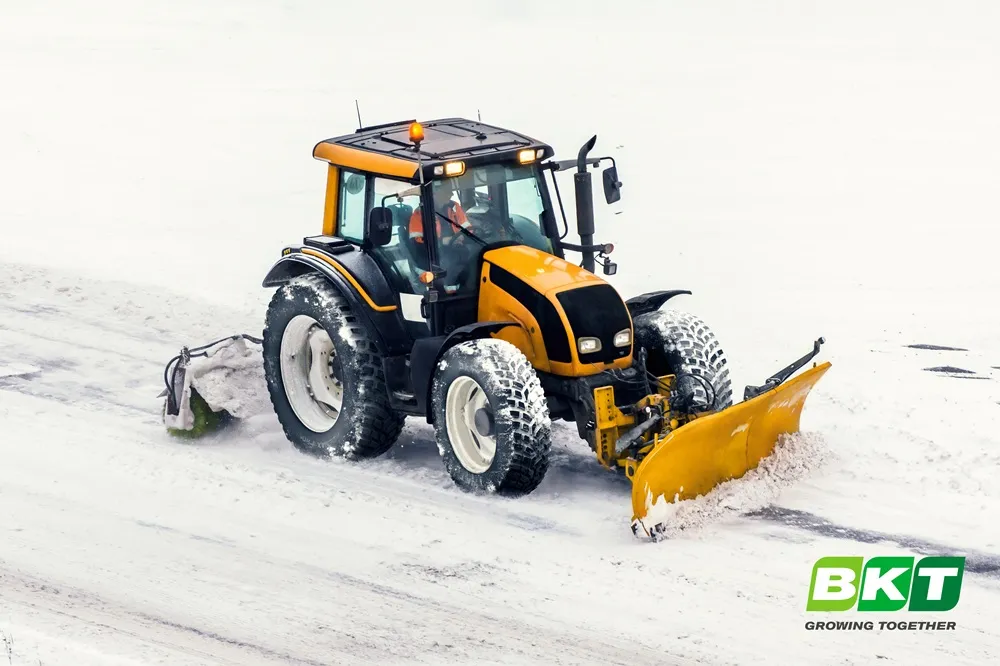 Yellow Tractor ploughing snow with BKT RIDEMAX FROST tyres