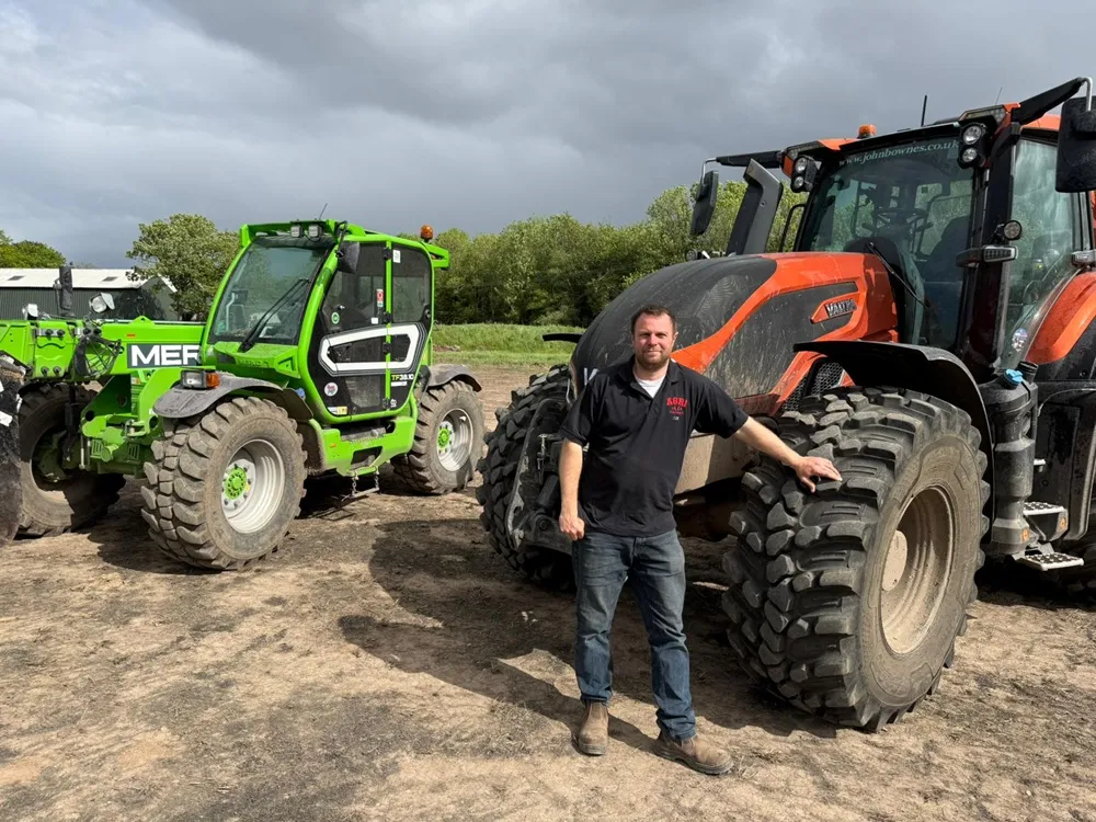 Image of a man stood in front of a red and green tractor